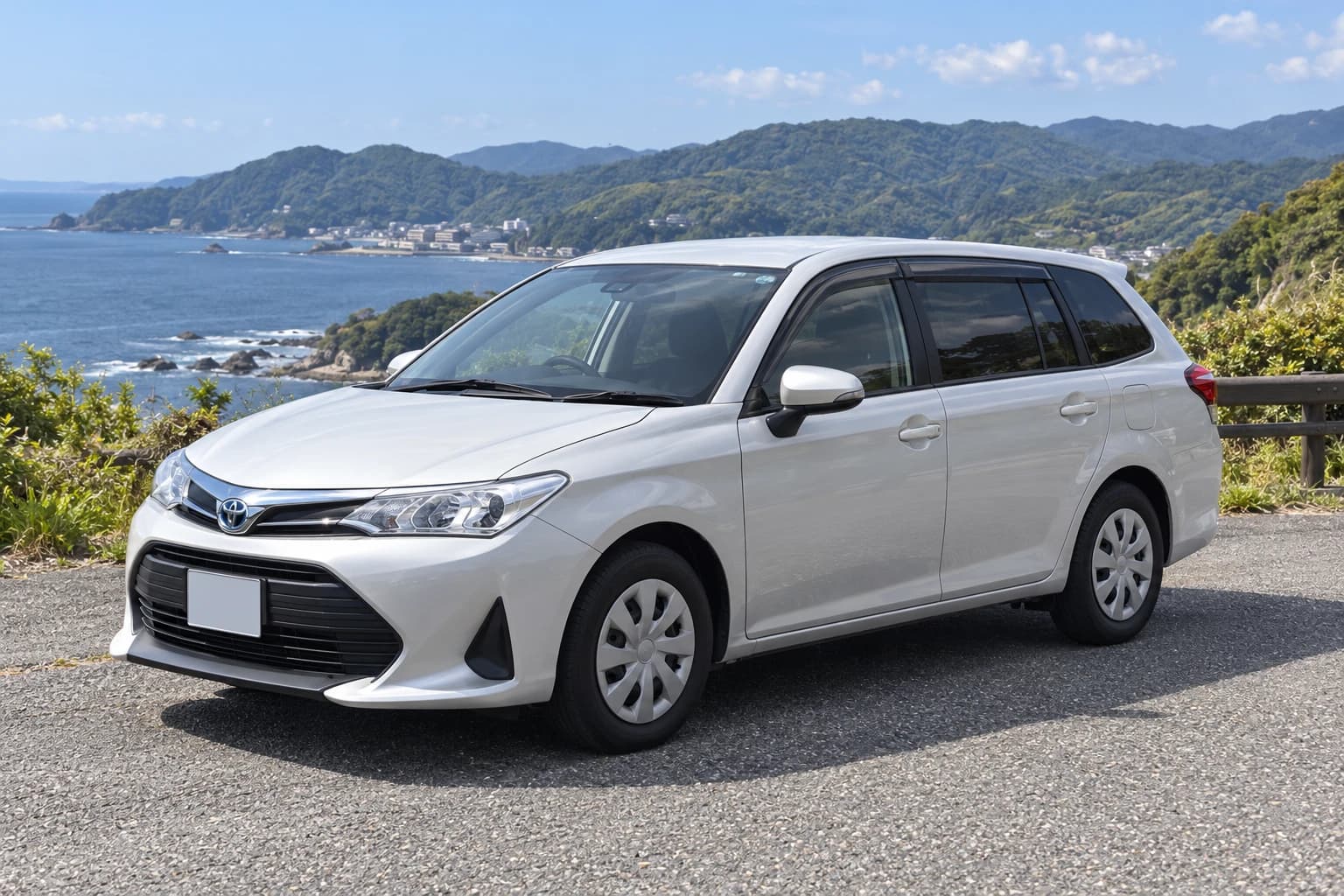 Белый Toyota Corolla Fielder E160 со штатными колёсными колпаками на приморской дороге