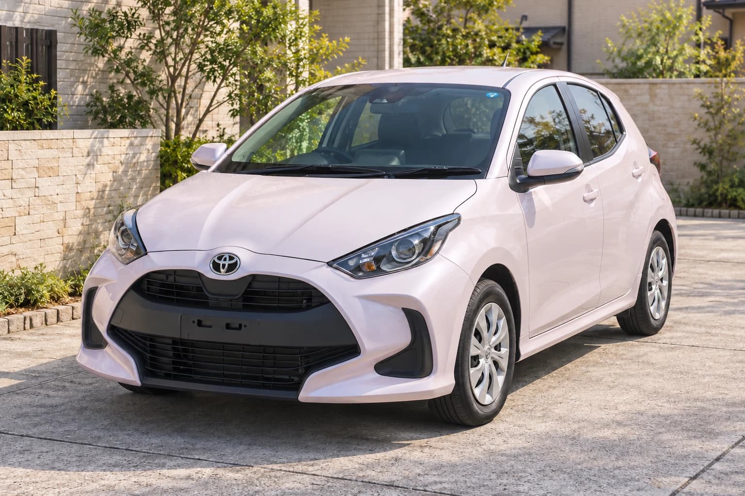 Светло-розовый японский Toyota Yaris XP210 у городского дома